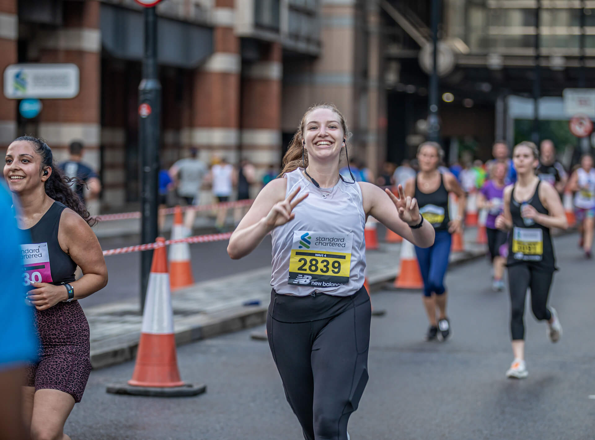 A woman smiles and makes V sign as she runs