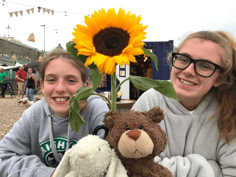 Two girls with teddy bears and a sunflower