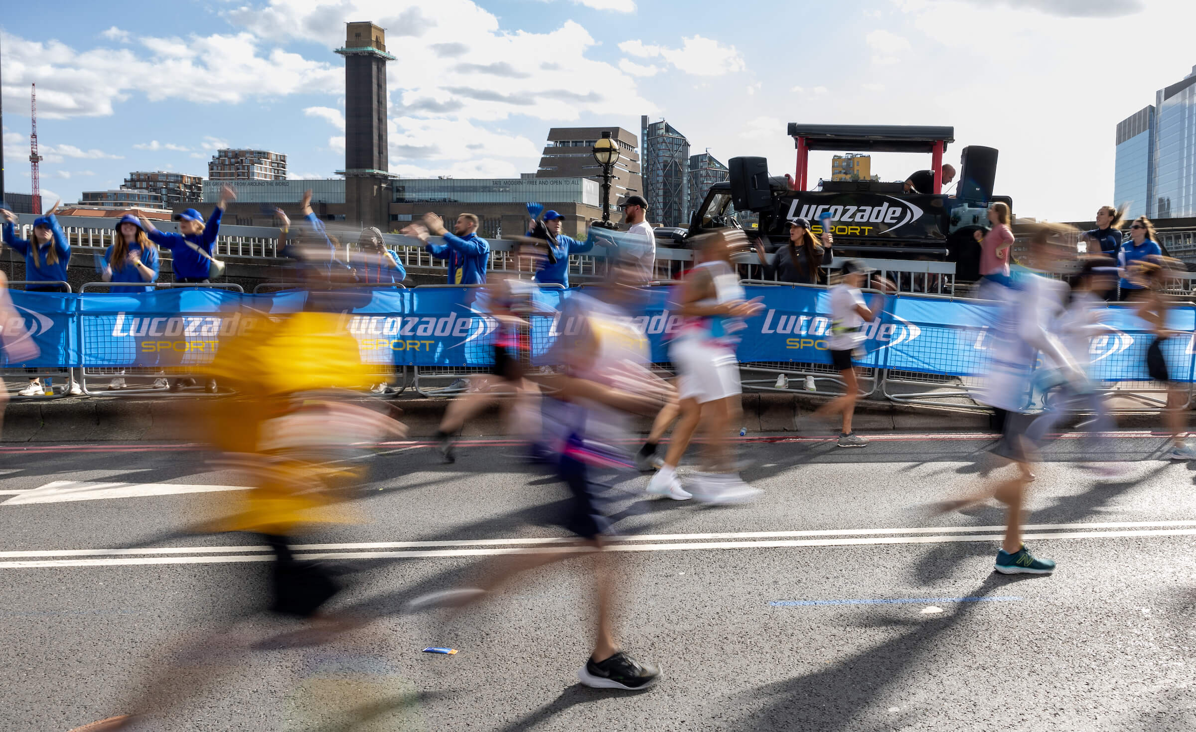 A blur of marathon runners passing a Lucozade Sport zone