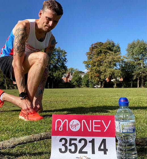 A runner with a bottle of Buxton Natural Mineral Water and their Virgin Money London Marathon running number