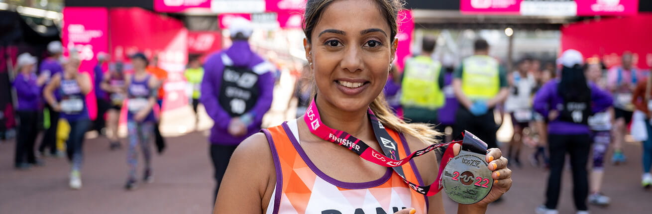 A woman shows her finishers medal at 2022 TCS London Marathon