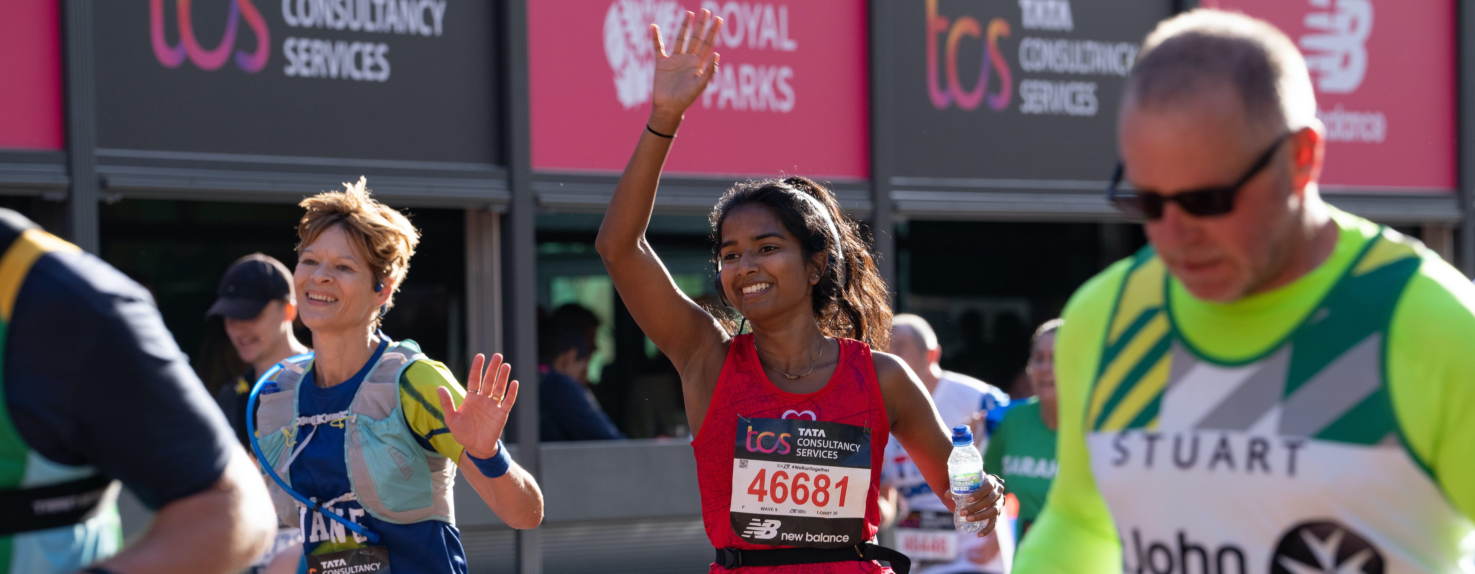 Participants wave as they move down The Mall at the TCS London Marathon