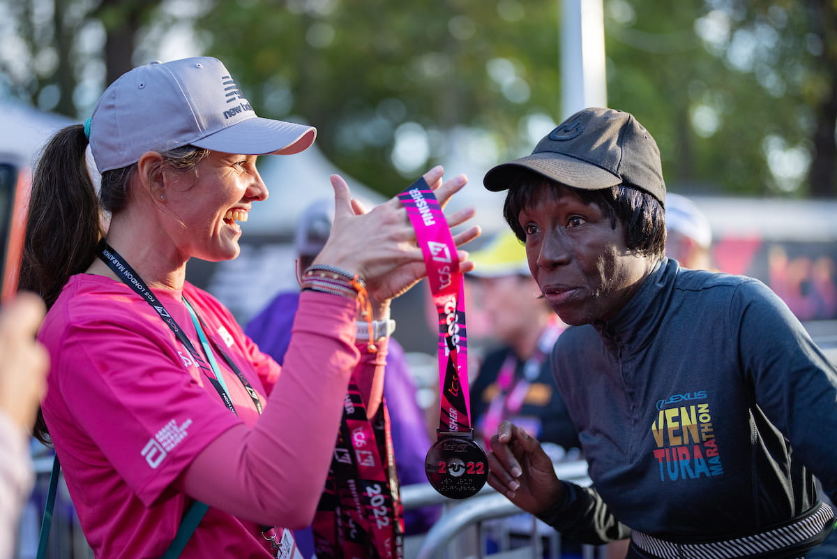 A volunteer awards a participant their TCS London Marathon finisher&#x27;s medal