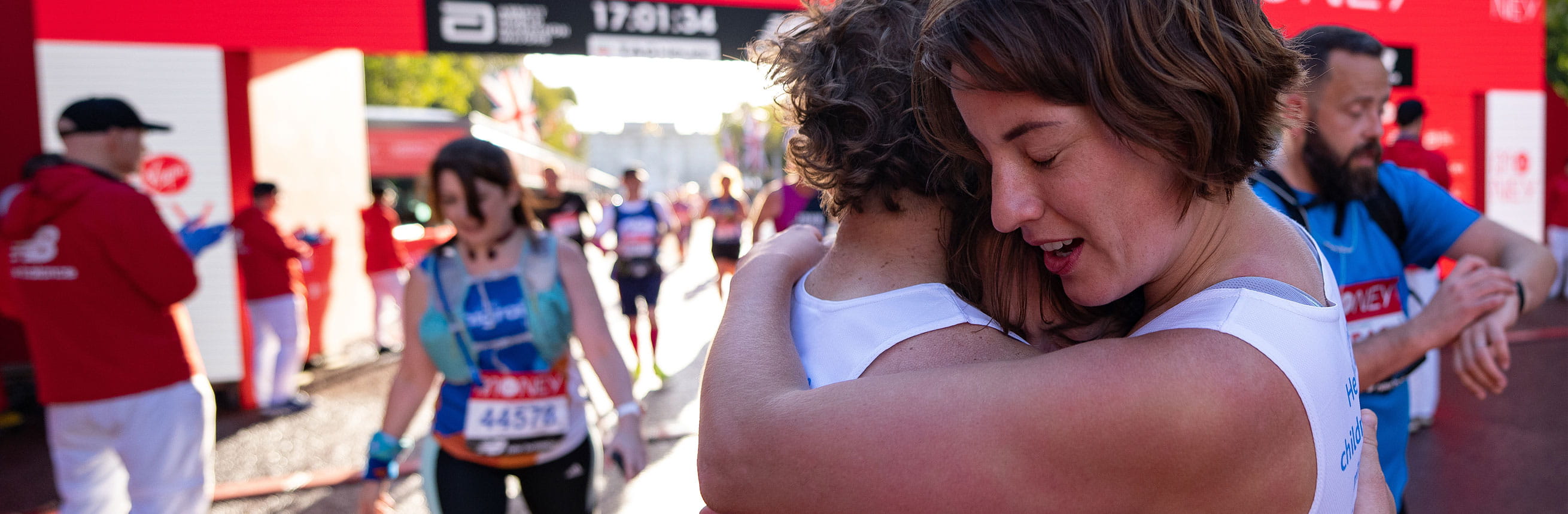 Mass runners hug at the finish line after completing The 2021 Virgin Money London Marathon