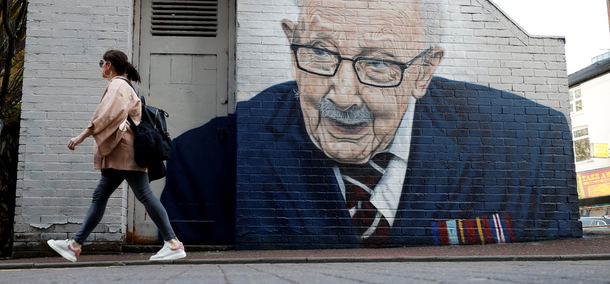 A woman walks past a new mural of British veteran and fundraiser Captain Tom Moore
