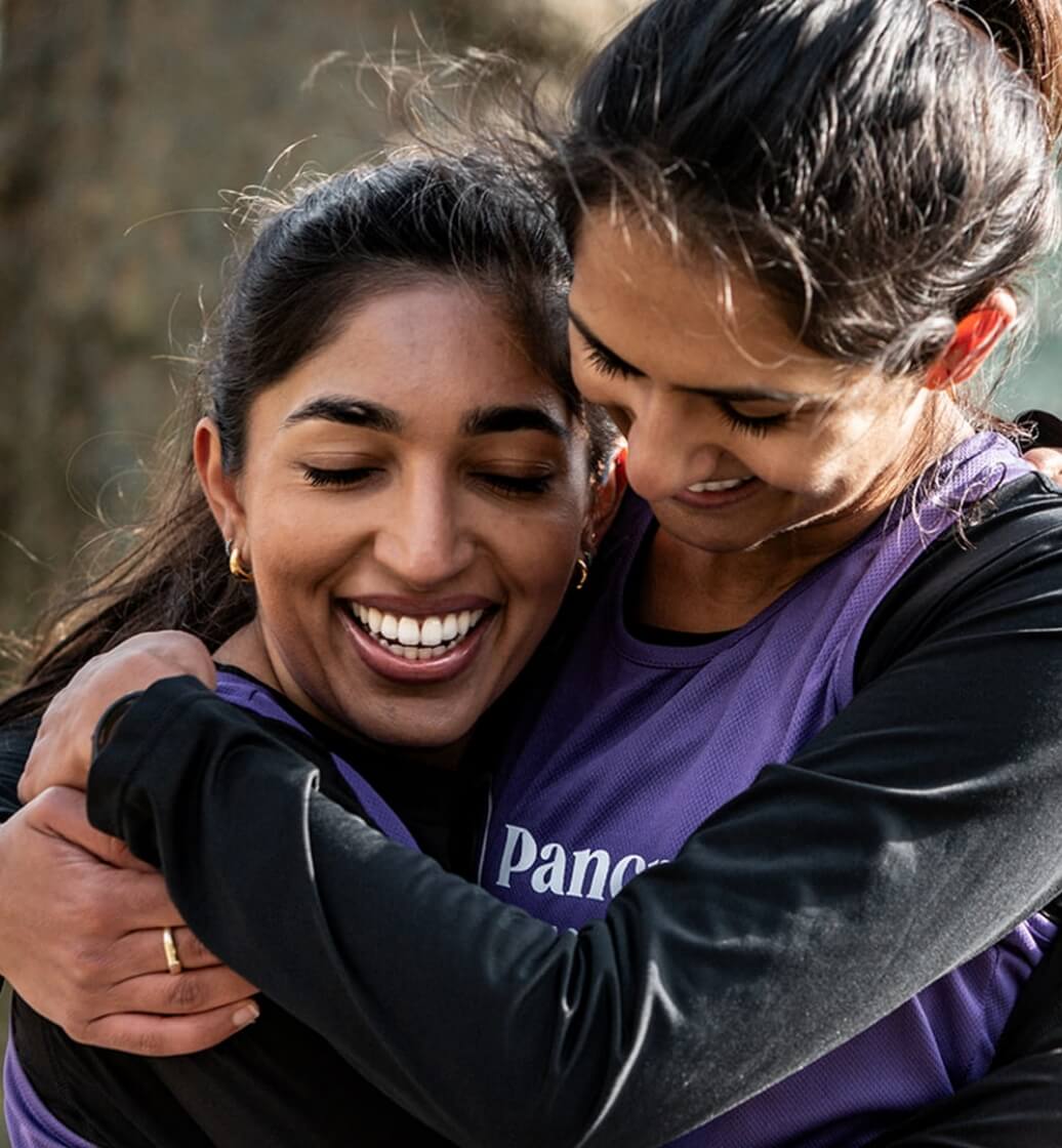 Two Pancreatic Cancer UK runners embrace whilst on a run in a park
