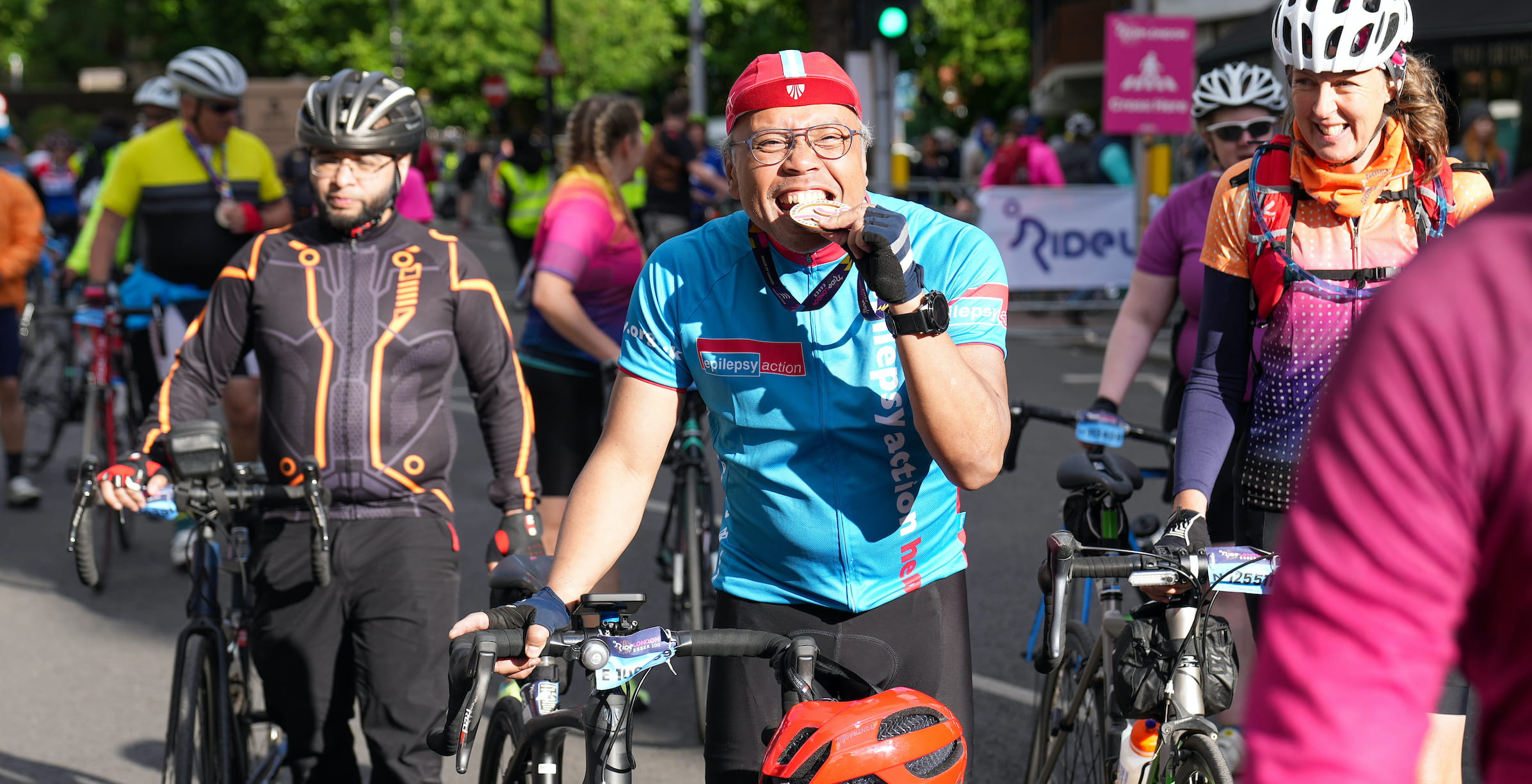 A rider bites their medal after completing the RideLondon-Essex sportive