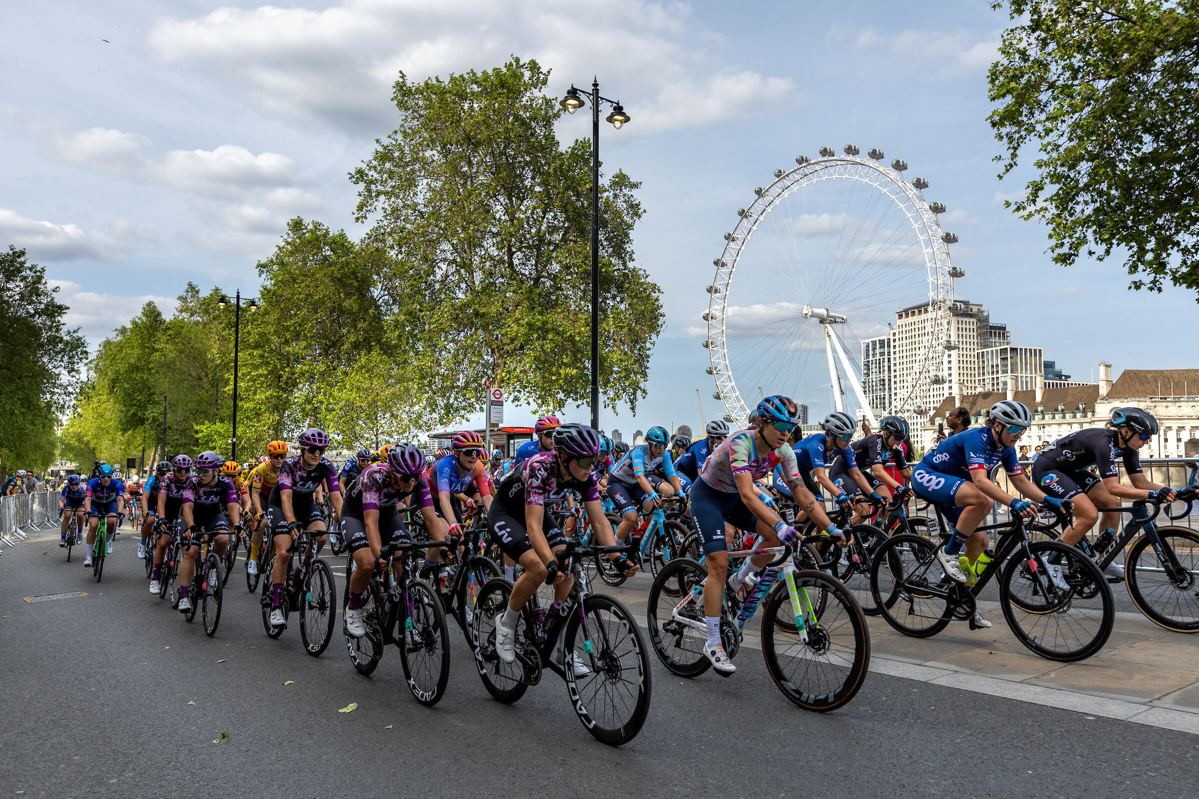 A peloton of pro cyclists rides down Embankment