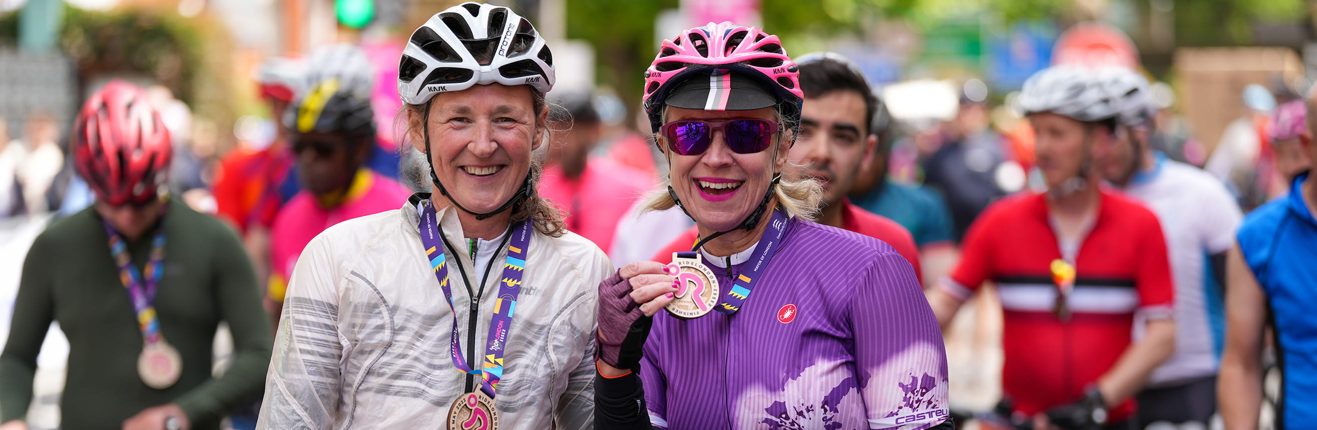 Two women showing their medals at the Finish line of RideLondon 2022