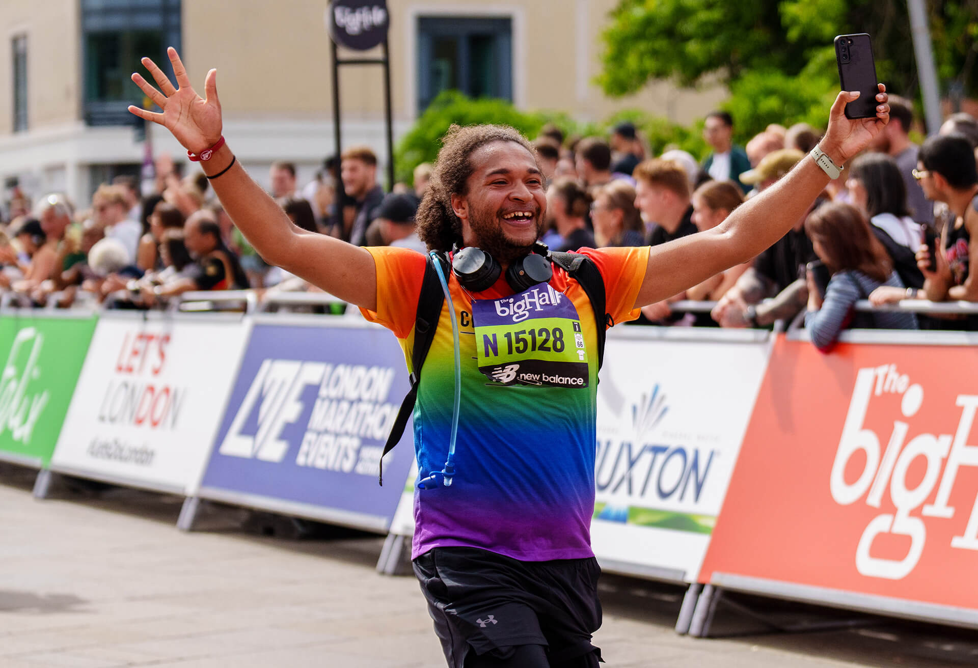 Man smiles with arms up as he runs The Big Half